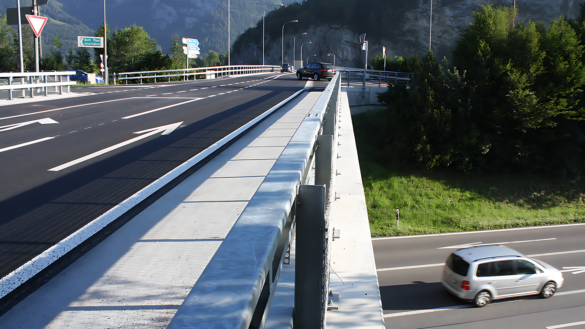 Blick vom Geländer der Brücke. Links im Bild ist die Brücke zu sehen, rechts im Bild die Autobahn unterhalb der Brücke