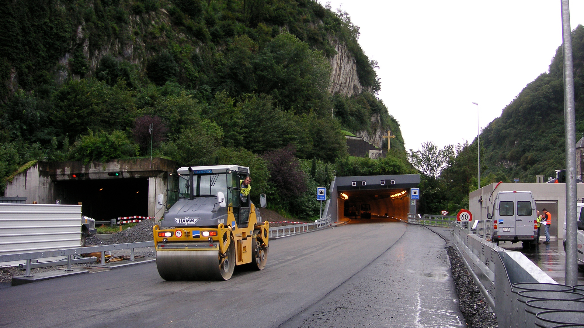 Un rouleau conduit sur la route. En arrière-plan, un portail d'un tunnel